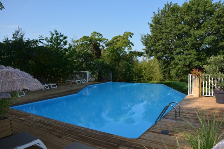 La piscine chauffée extérieure et sa magnifique plage en bois, tout entourée de verdure