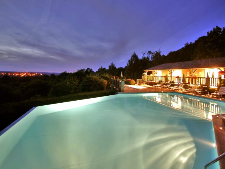 Crépuscule enchanteur, avec la Bastide Royale de Domme étincelant à l'horizon de la piscine à débordement