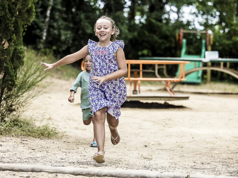 Enfants qui courent vers l’aire de jeux du camping pendant une cousinade
