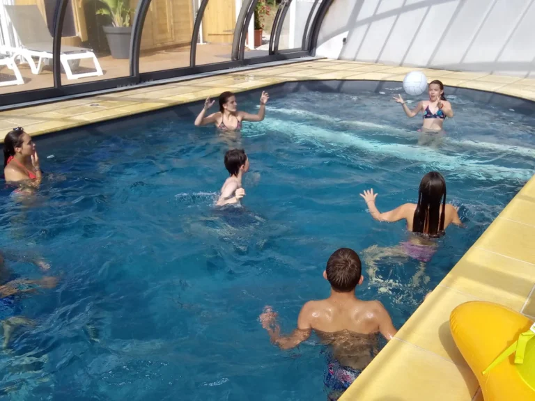 Enfants qui jouent dans la piscine intérieure chauffée du camping en Dordogne