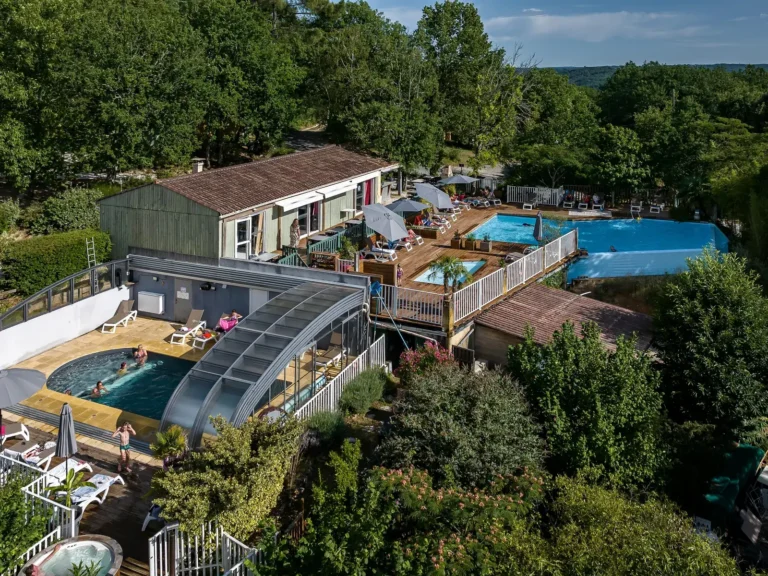 Vue drone de la piscine couverte, de la piscine extérieure et du spa du camping à Domme